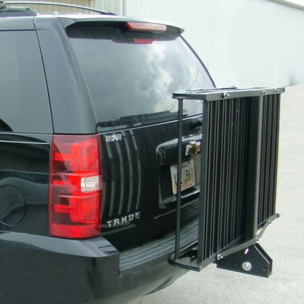 Folding Mighty Lite Aluminum Scooter and Power Chair Carrier (Blemished) attached to the back of a black vehicle, showcasing its bike rack and scooter-loading features with a close-up of the red tail light.