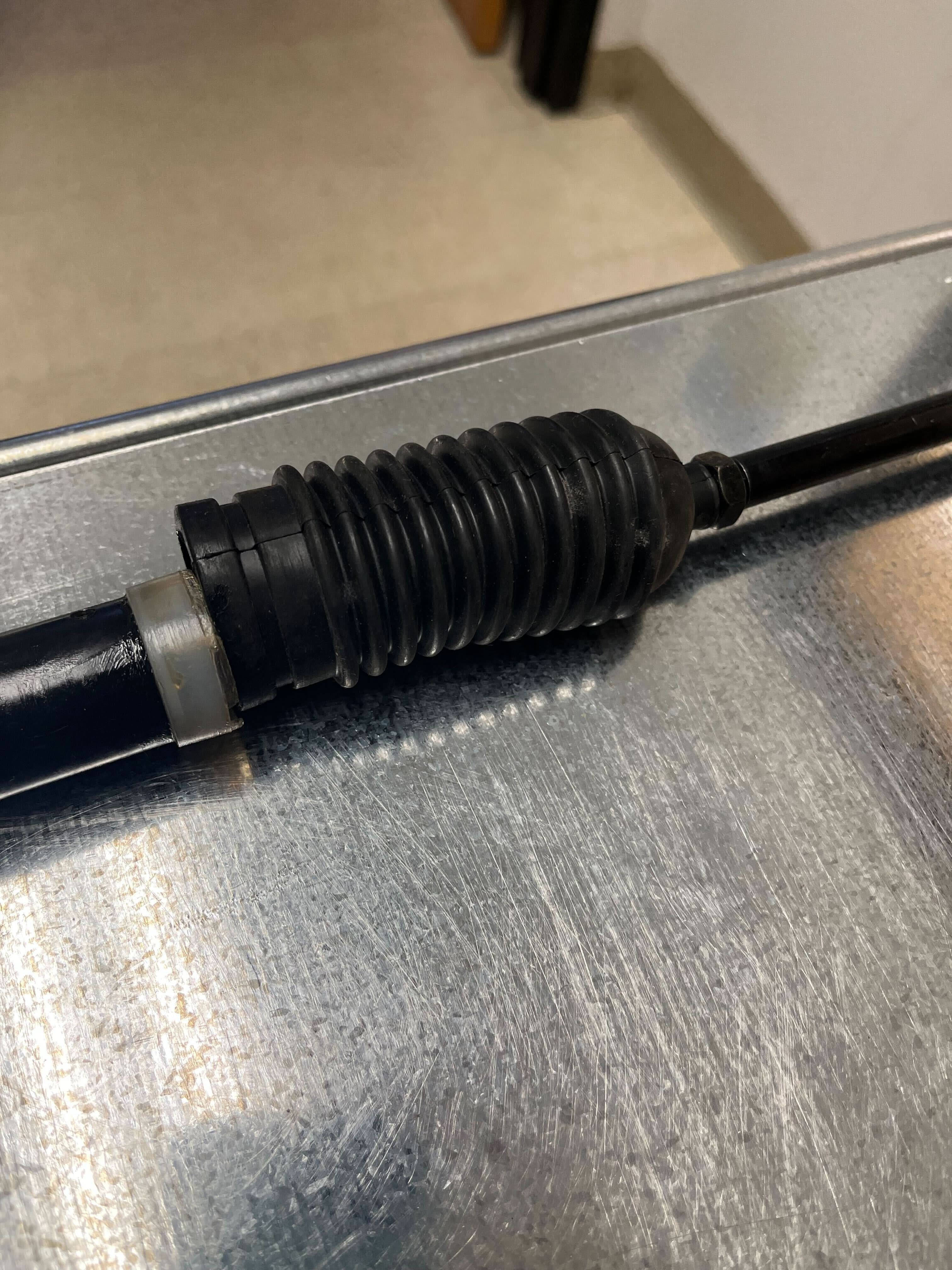 Steering Gear Assembly for Coleman KT196 196cc 6.5 Hp Go-Kart (Blemished) on a metal surface, featuring a black rubber tube, cables, and tools.