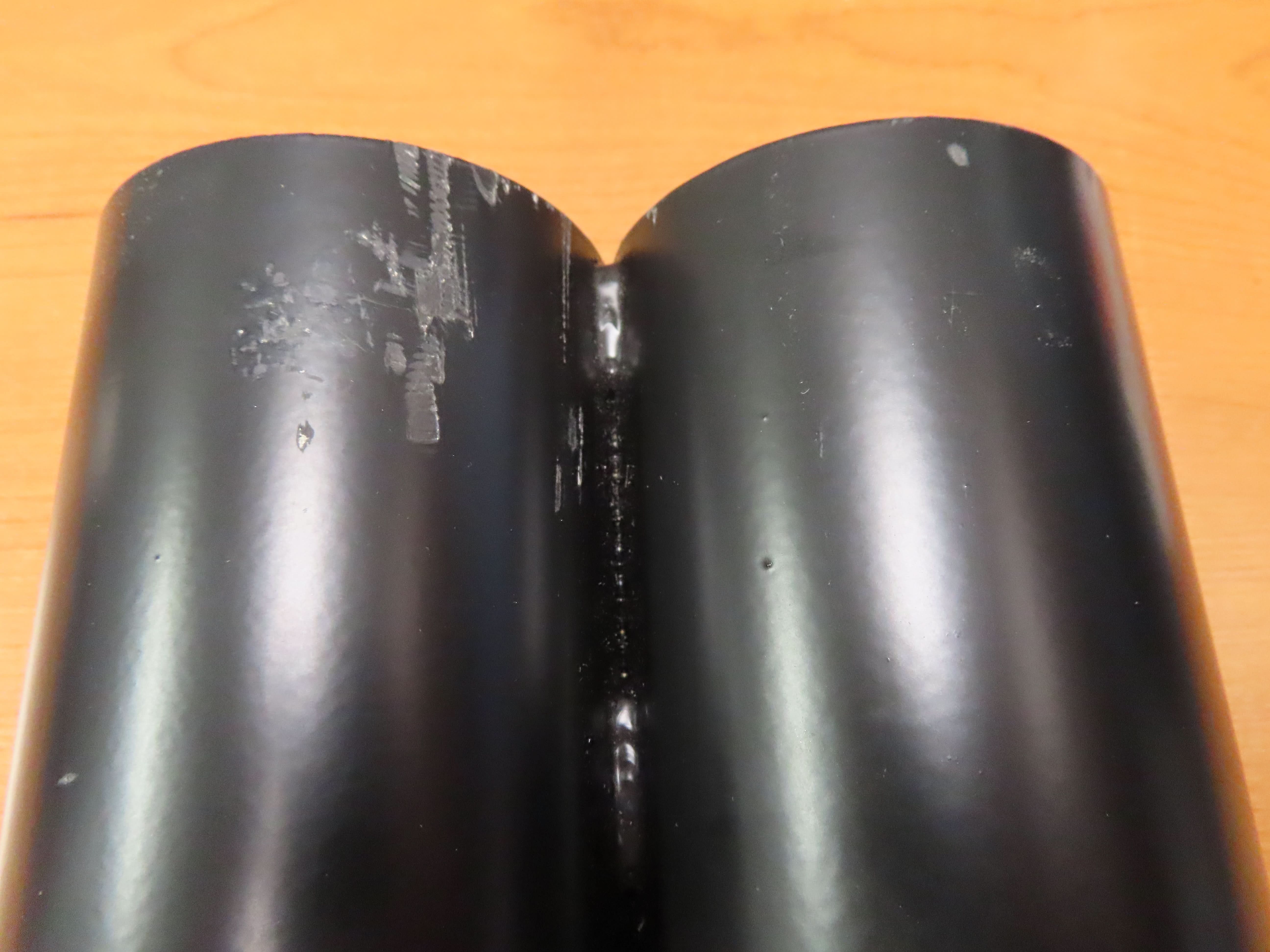 Crutch Holder for Pride Mobility Scooters (Blemished), featuring a black tube with a crack in the corner, resting on a wood surface. Suitable for 3 diameters, available with one or two tubes.
