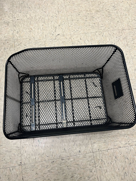 Market-Style Rear Basket for Bicycles (Axiom) on a tile floor, showcasing its black vinyl-dipped steel wire mesh construction and open top design.