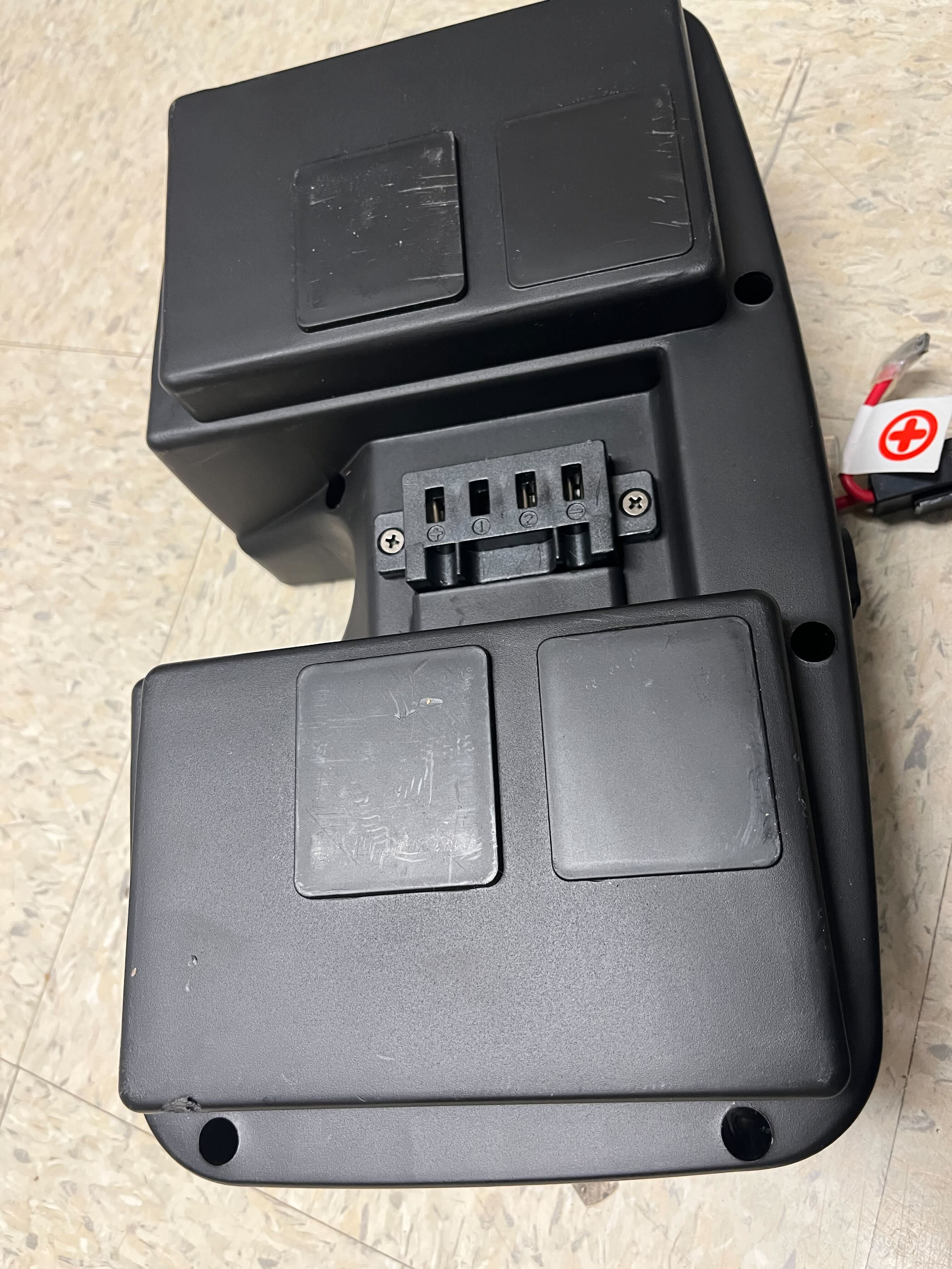 Battery Box Assembly for ActiveCare/Drive Medical Spitfire EX & Spitfire Pro SE Scooters (Blemished), featuring a black rectangular device with buttons and holes, designed to securely hold scooter batteries.