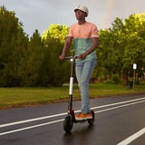 Man riding a scooter on a road, highlighting the need for a Coaxial Charger Port for GOTRAX GXL, GXL V2, G4, Flex, & XR Ultra Electric Scooters, essential for maintaining battery charge.