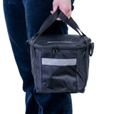 A person holding the Insulated Front Basket Bag for Mobility Scooters, showcasing its sturdy ripstop polyester material, zippered main compartment, and leather label.