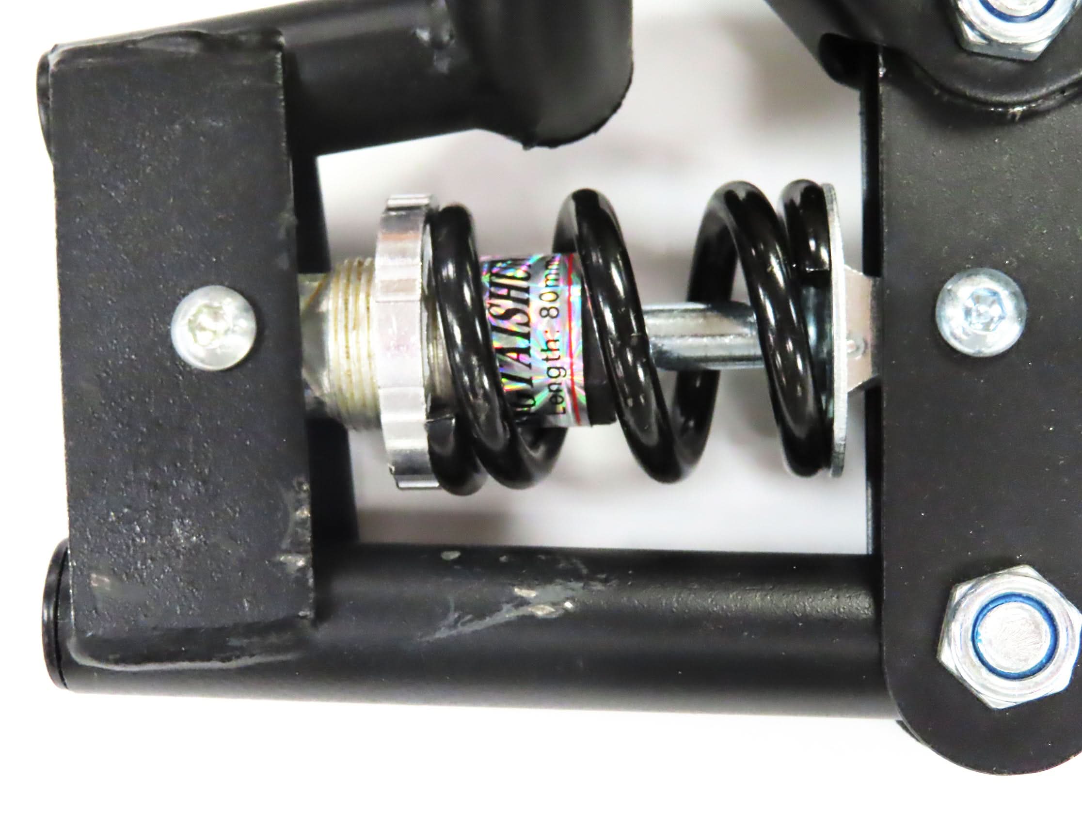 Deluxe Hoverboard Go-Kart Attachment Kit with Large Front Wheel & Suspension (Blemished), showing black metal frame, spring, front wheel, and handlebar levers. Visible scratches and scrapes on the black enamel finish.
