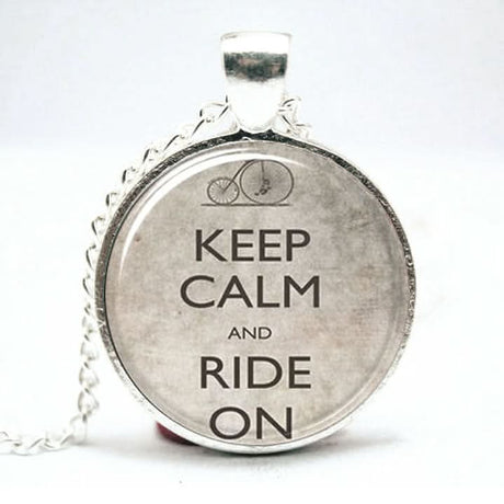 Keep Calm and Ride On Pendant & Chain featuring a silver plate finish, domed glass, and a 16 chain with a 1 diameter pendant, perfect for cyclists and steampunk enthusiasts.