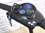 Deluxe Easy Pull Key for Pride and Go-Go Mobility Scooters shown attached to a bicycle handlebar, featuring a round black plastic knob and finger ring for easy handling.