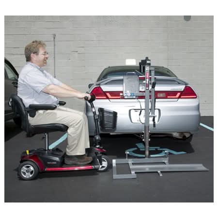 Man utilizing the Pride Silver Star Power Tote Mini PT-150 Scooter Lift, attached to a car, to transport a small travel scooter.