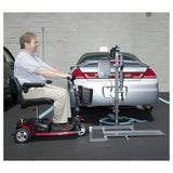 Man utilizing the Pride Silver Star Power Tote Mini PT-150 Scooter Lift, attached to a car, to transport a small travel scooter.